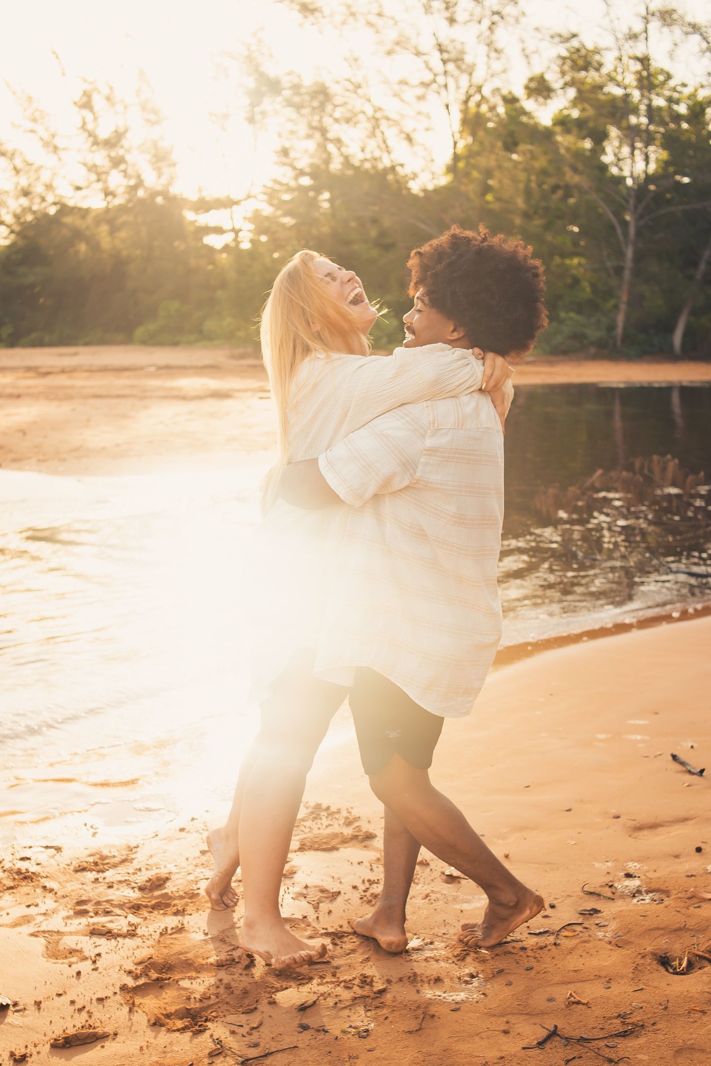 A laughing couple holding each other close at sunset